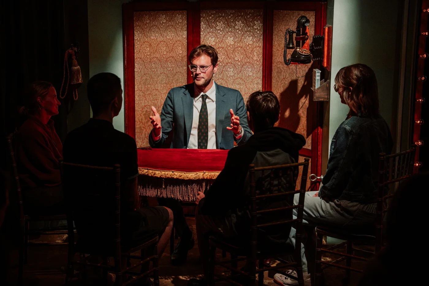 Kevin performing for a small group around a red tabletop in a warmly lit room