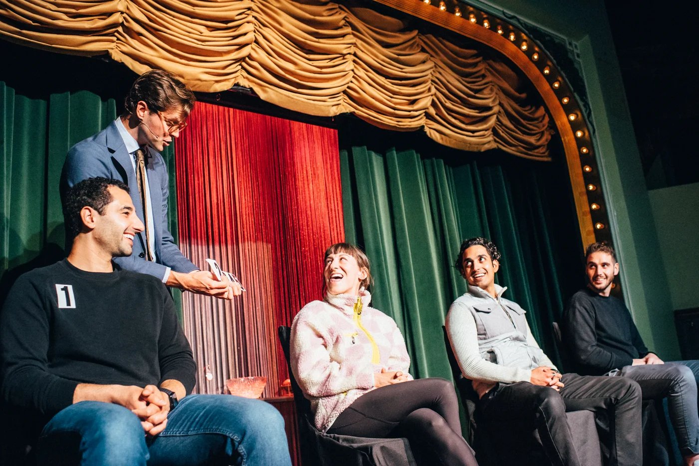Kevin performs with four smiling guests beneath the Palace Theater’s gold curtains