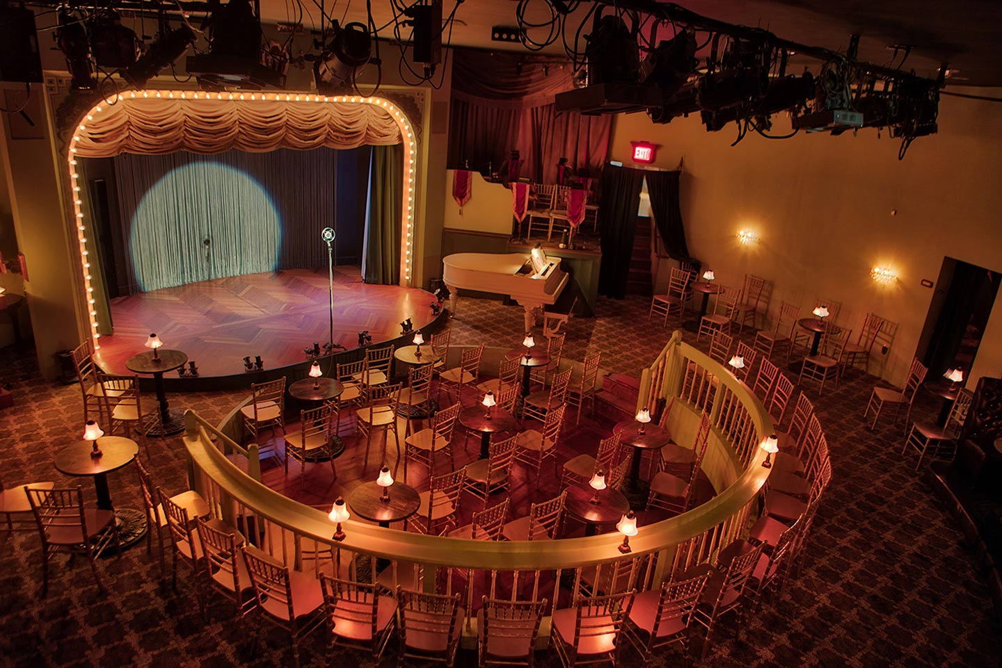 The cabaret stage and tables beneath the Palace Theater’s gold curtains