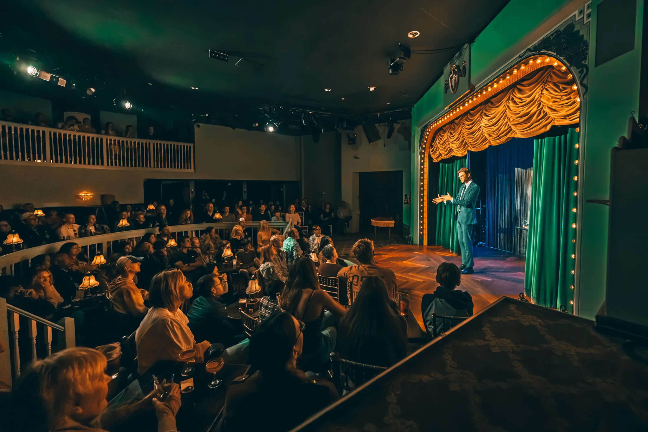 Guests gathered at candlelit tables in the Palace Theater, facing the velvet-curtained stage